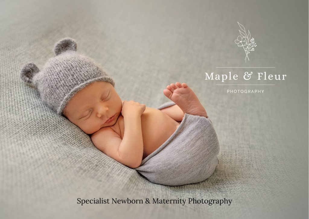 photo of baby wearing hat with ears, partially swaddled in a blanket